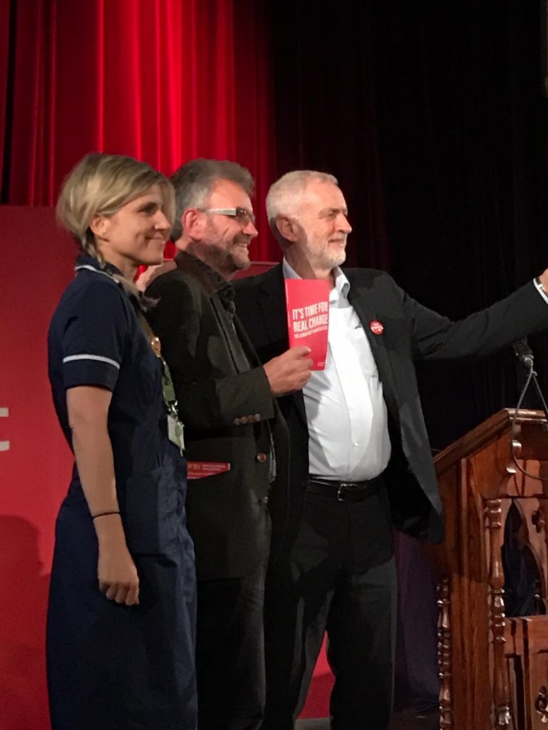 Peter Chowney, Antionia Berelson and Jeremy Corbyn standing together, with manifesto
