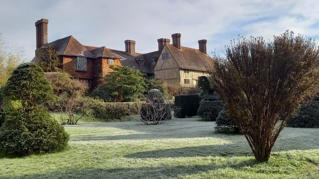 Dixter House with frosty lawns in foreground, from topiary garden